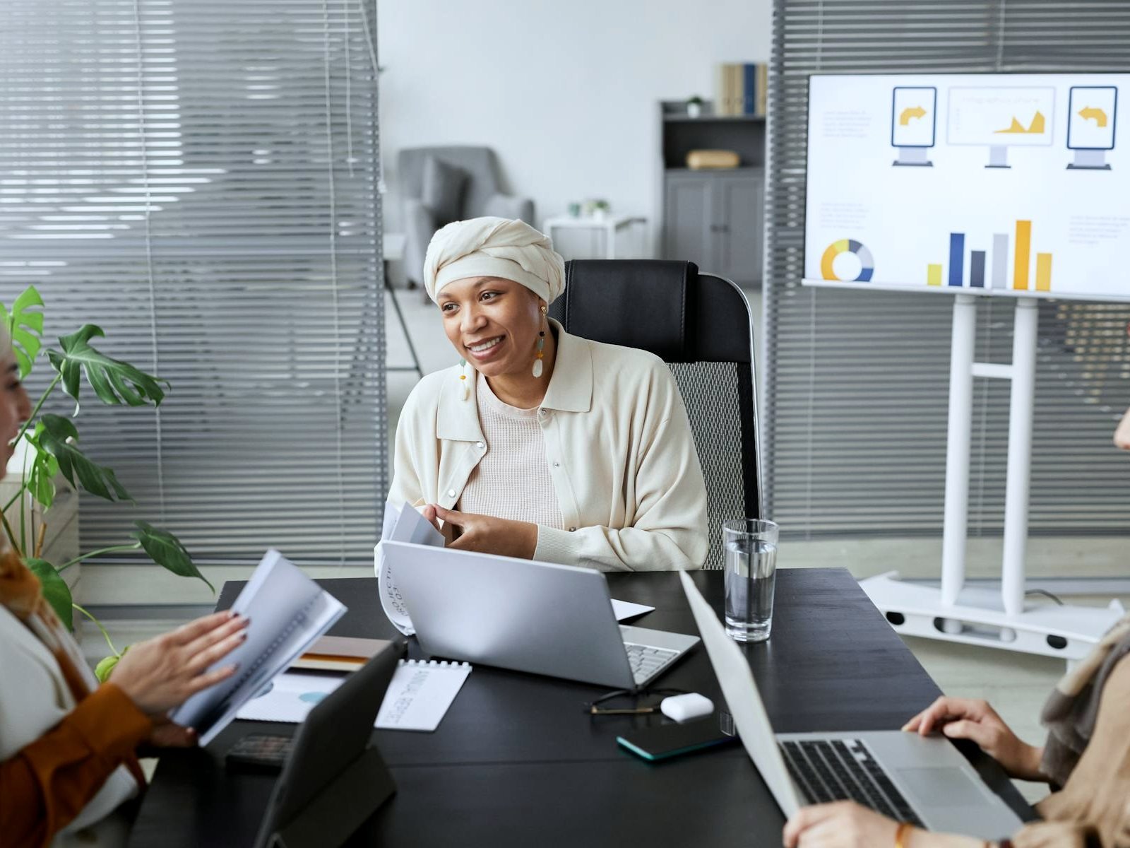 Business team in a neutral office meeting with laptops and performance charts